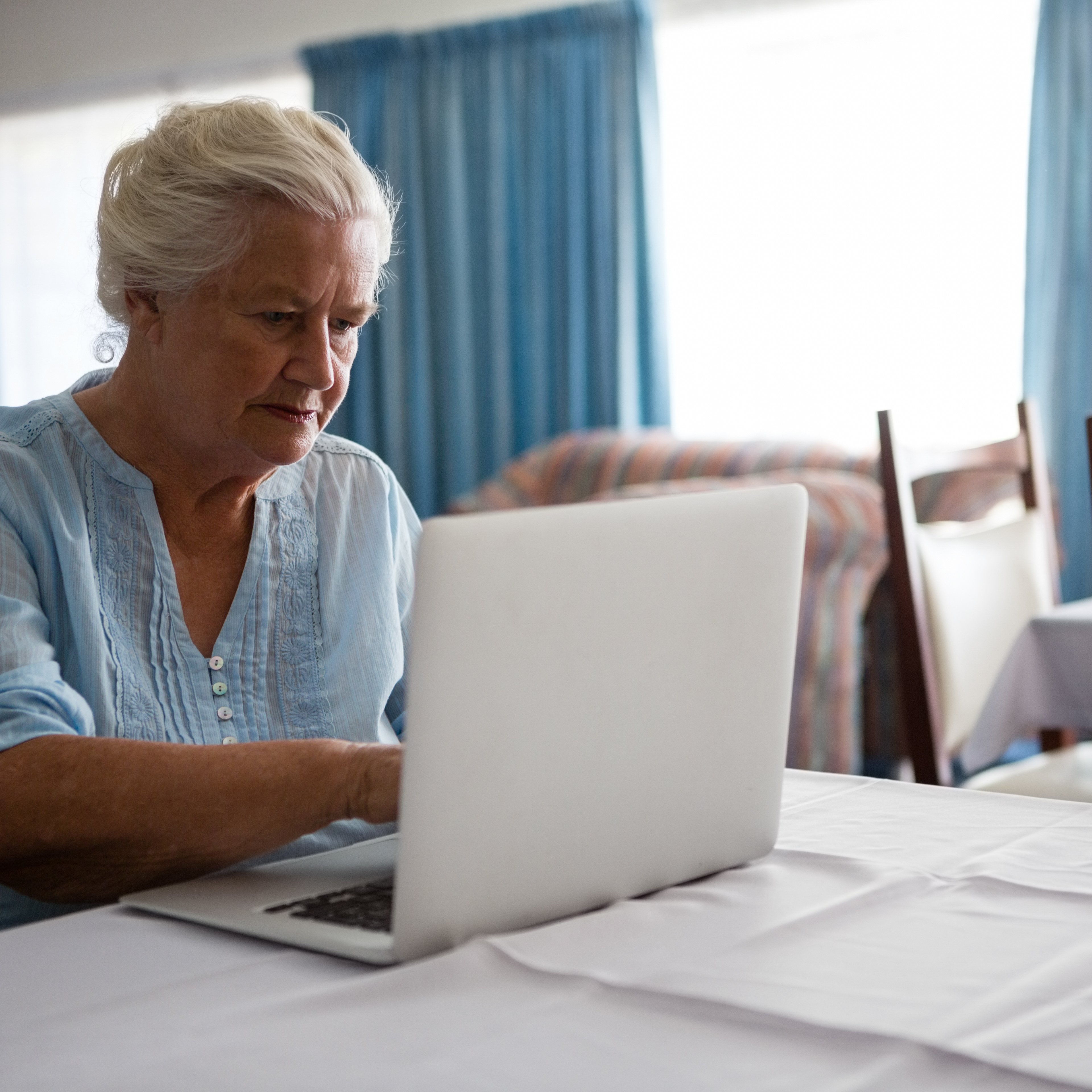Senior woman using laptop while sitting in nursing home Senior woman using laptop while sitting at table in nursing home